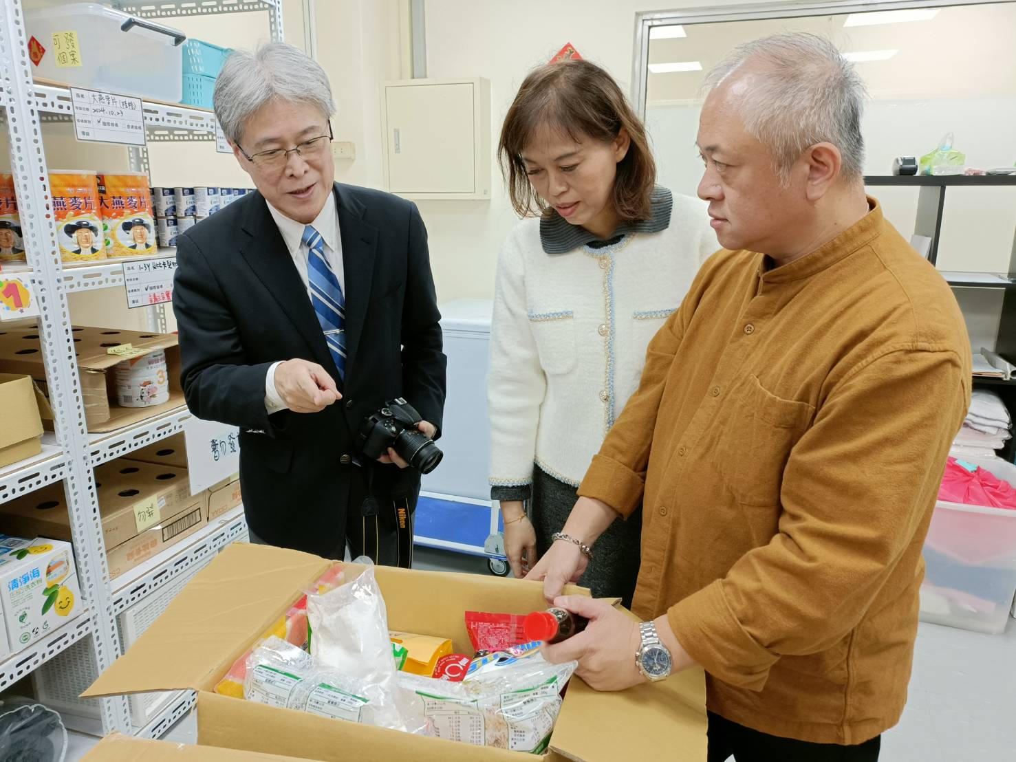 三重社福中心主任張信熙(右)向日詰一幸(左)說明實物箱的內容物